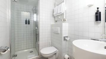 A modern bathroom with a glass-enclosed shower, a toilet, a sink, and a towel rack.