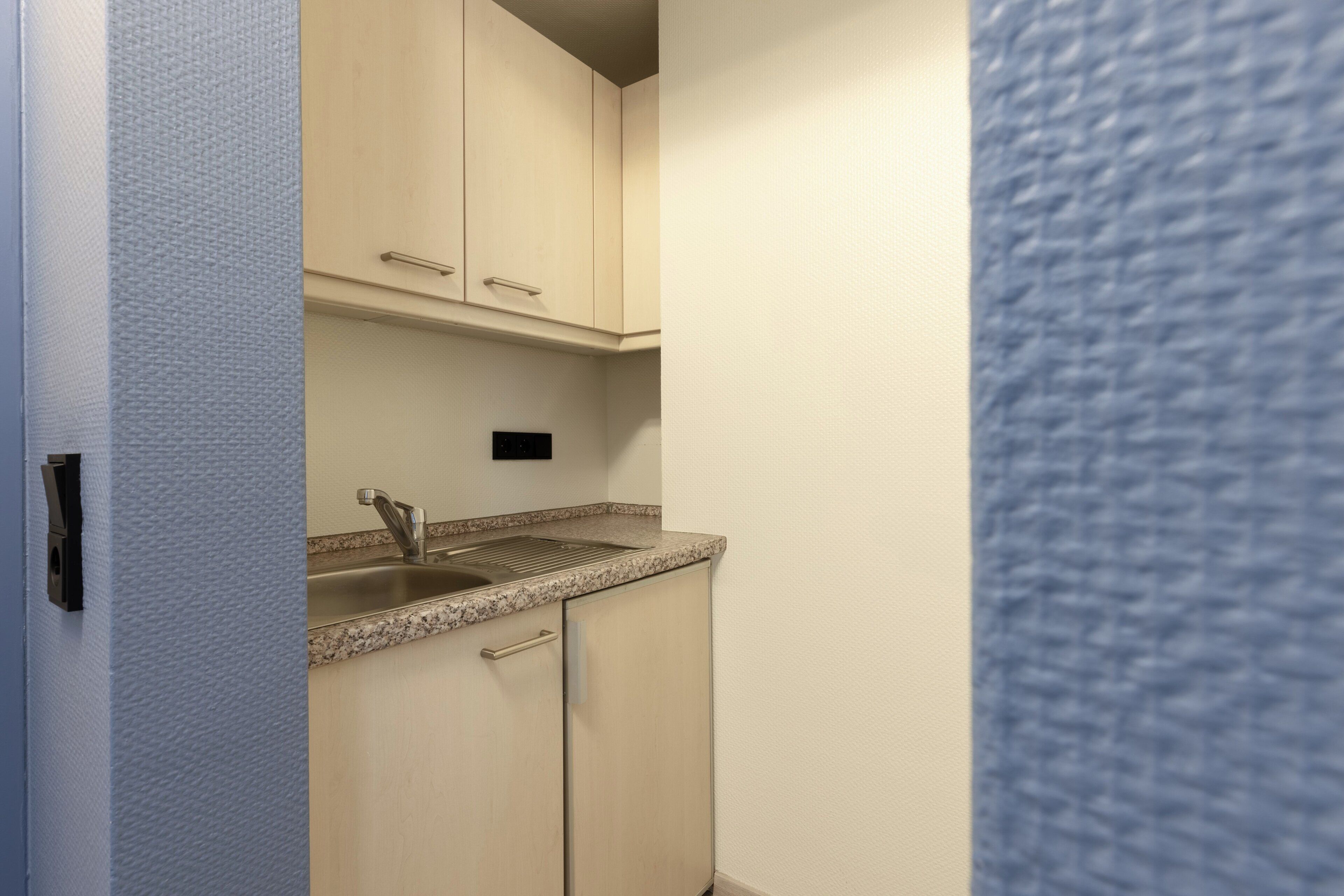 A small kitchenette with a sink, cabinets, and a countertop.