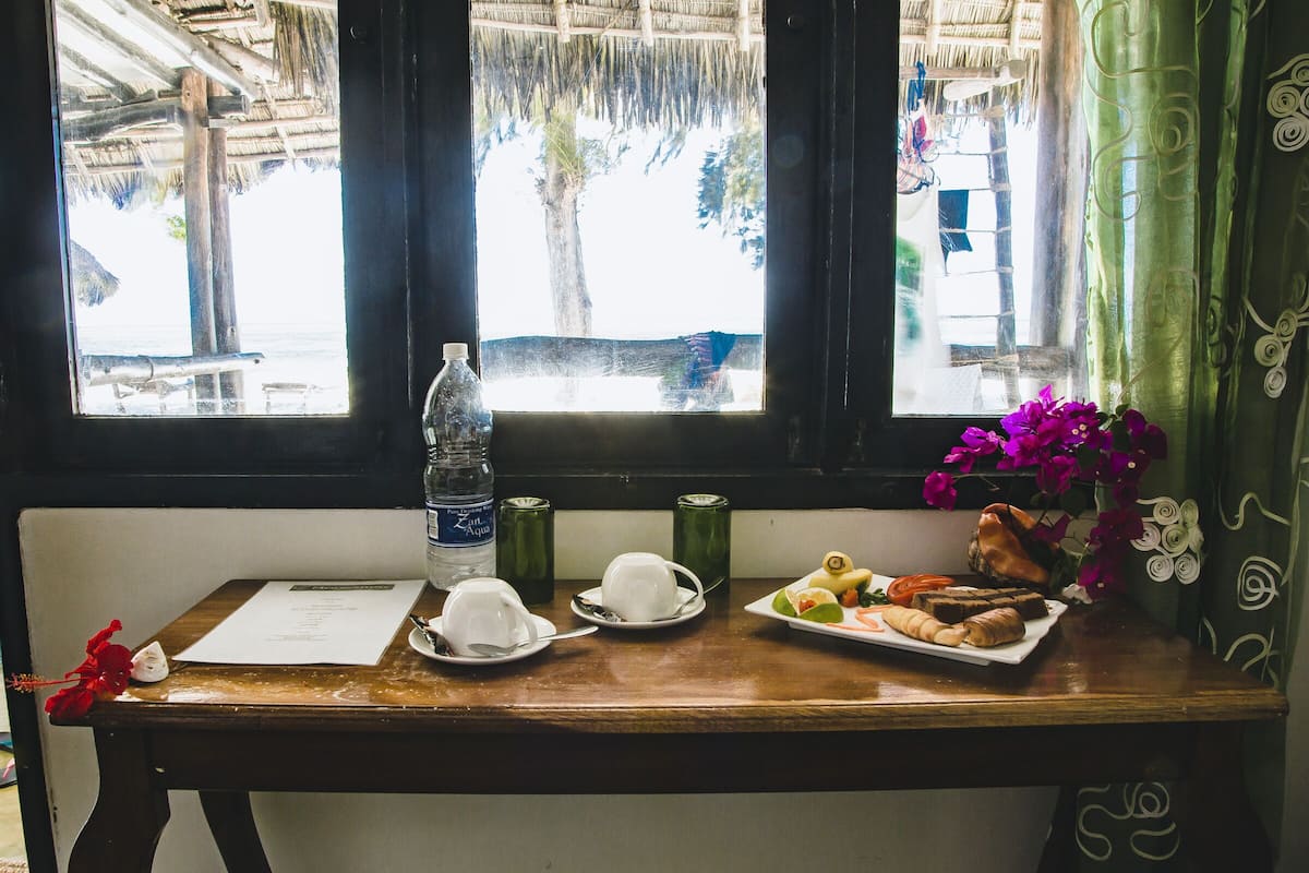 Une table en bois avec un menu, une bouteille d’eau et une assiette de nourriture.