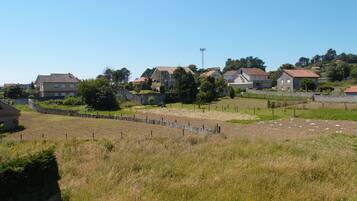 A residential area with houses, a fenced field, and a clear sky.