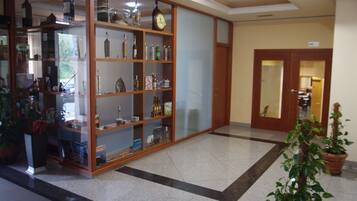 Un hall d’entrée avec une vitrine en verre contenant diverses bouteilles et une horloge au mur.