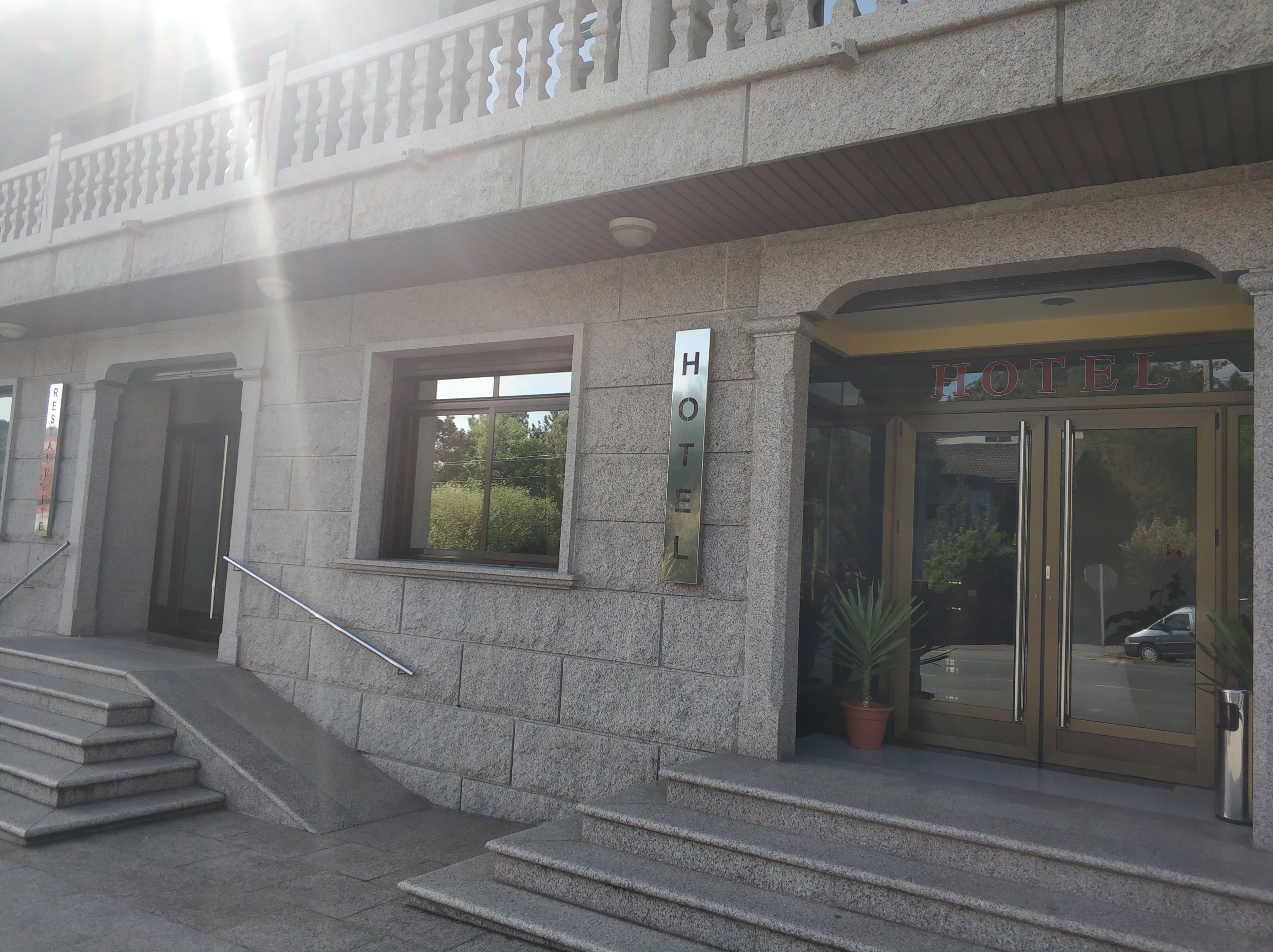 A hotel entrance with a stone facade, a sign indicating a restaurant, and a staircase leading up to the entrance.