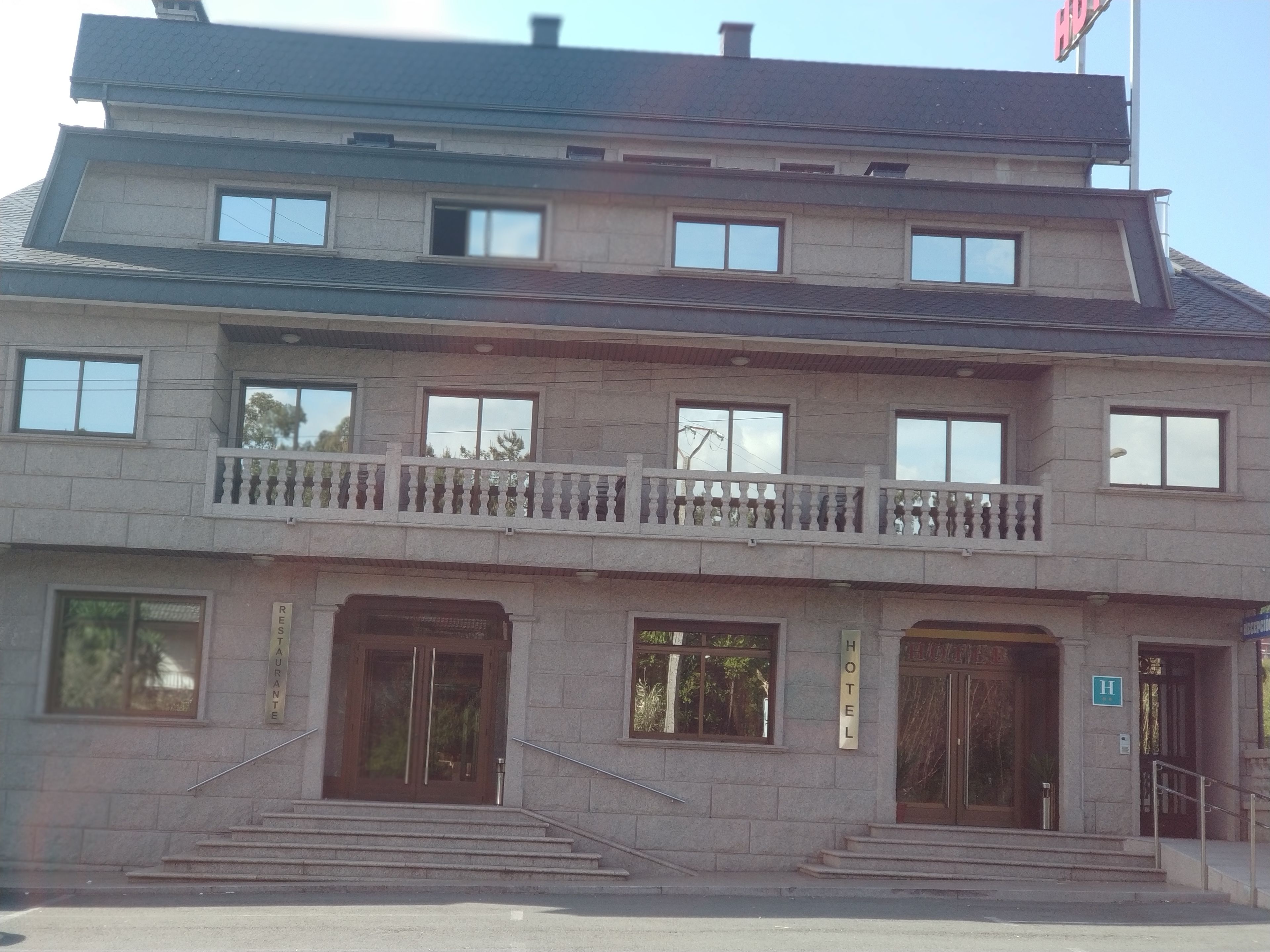 Un edificio a due piani con un balcone al secondo piano. Sono presenti due ingressi principali, uno al piano terra e uno al secondo piano.