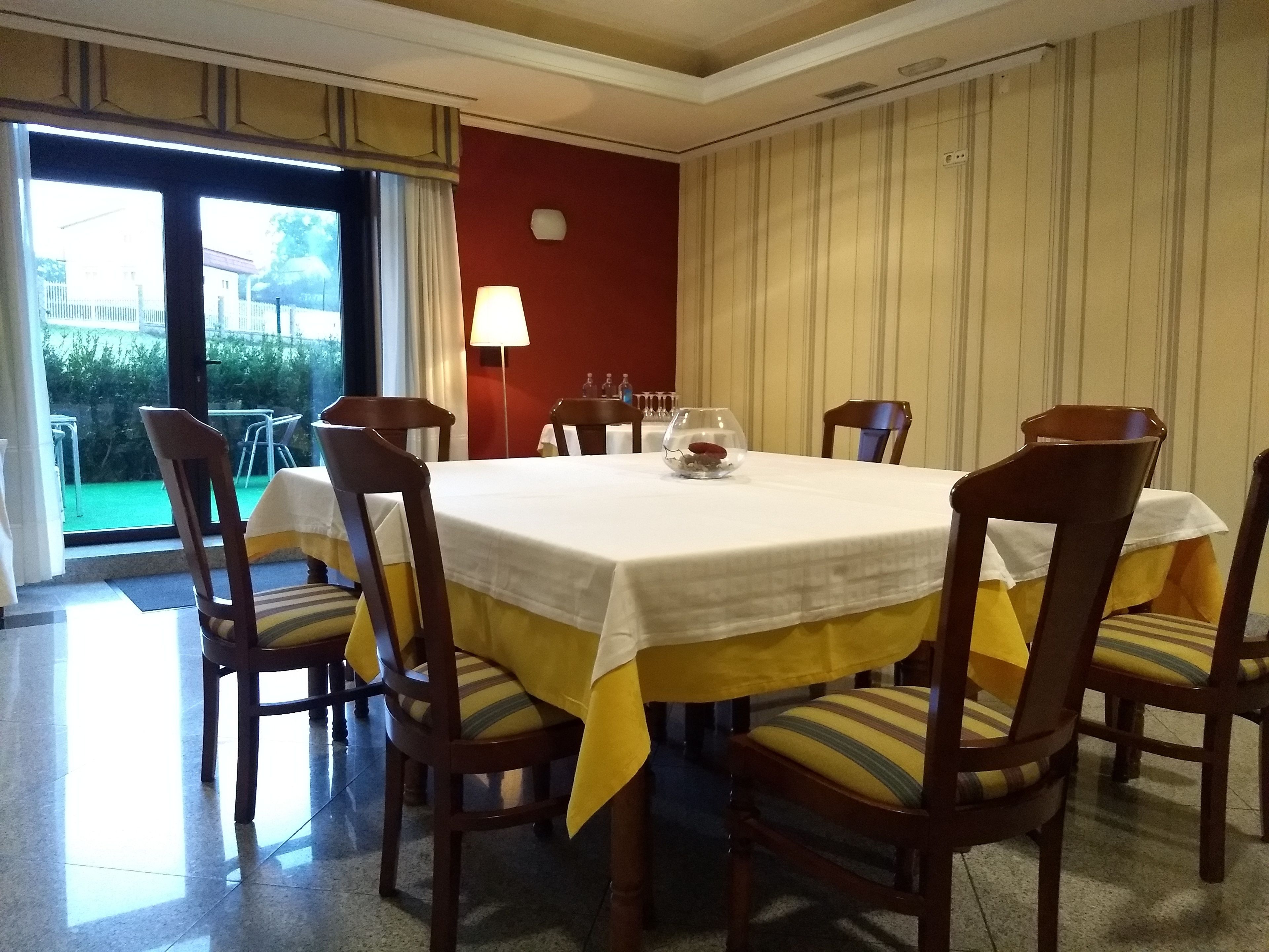 A dining area with a round table, six wooden chairs, and a yellow tablecloth.