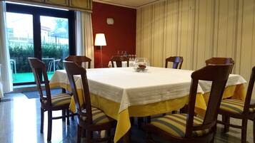 Een eethoek met een ronde tafel, zes houten stoelen en een geel tafelkleed.