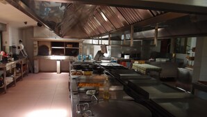 A commercial kitchen with stainless steel appliances, a large stove, and a pizza oven. - Hotel Avión Vigo (Vigo)