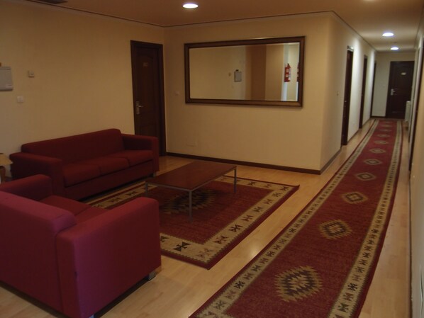 A living room with a red sofa, a coffee table, and patterned rugs. - Hotel Avión Vigo (Vigo)