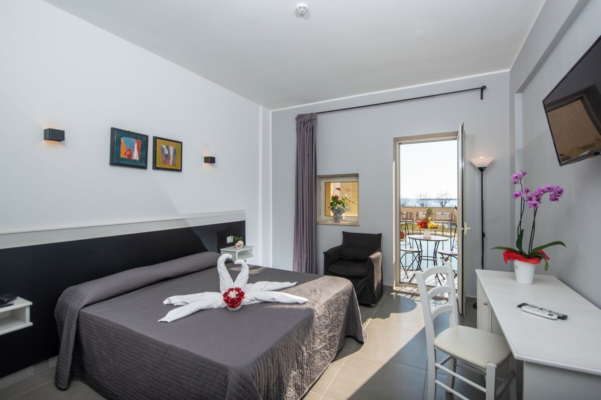 Una habitación de hotel moderna con una cama grande, un escritorio y un balcón con vistas.