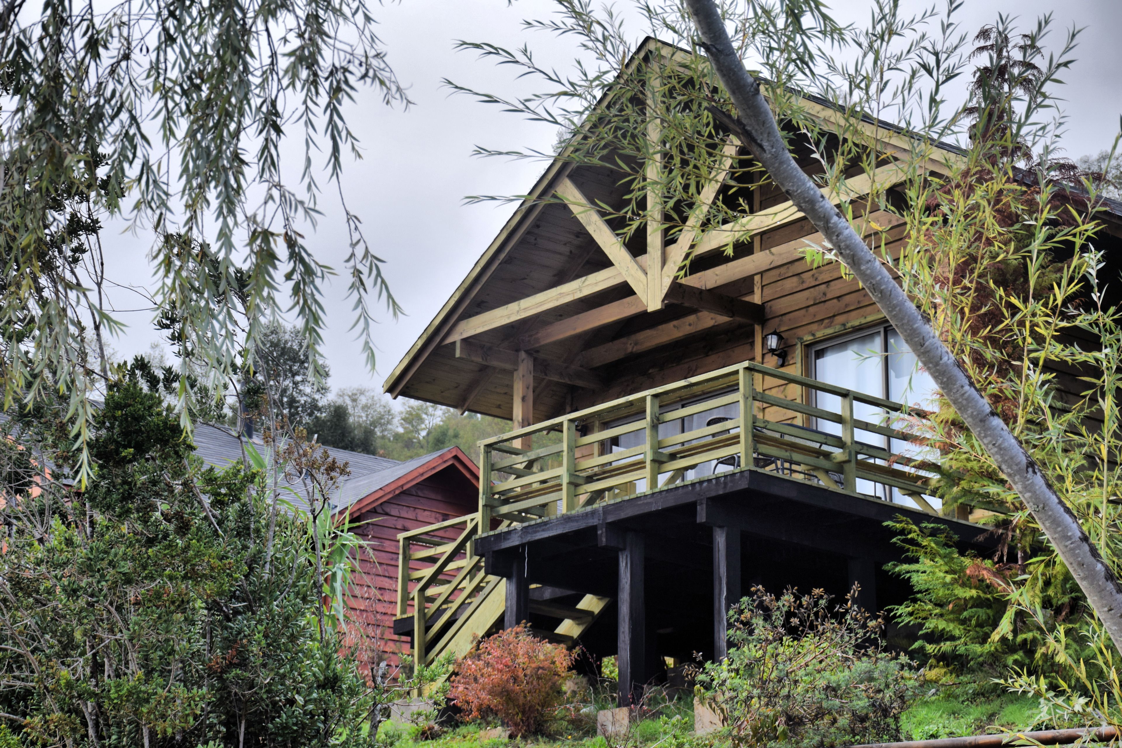 A wooden cabin with a balcony and stairs leading to the entrance.