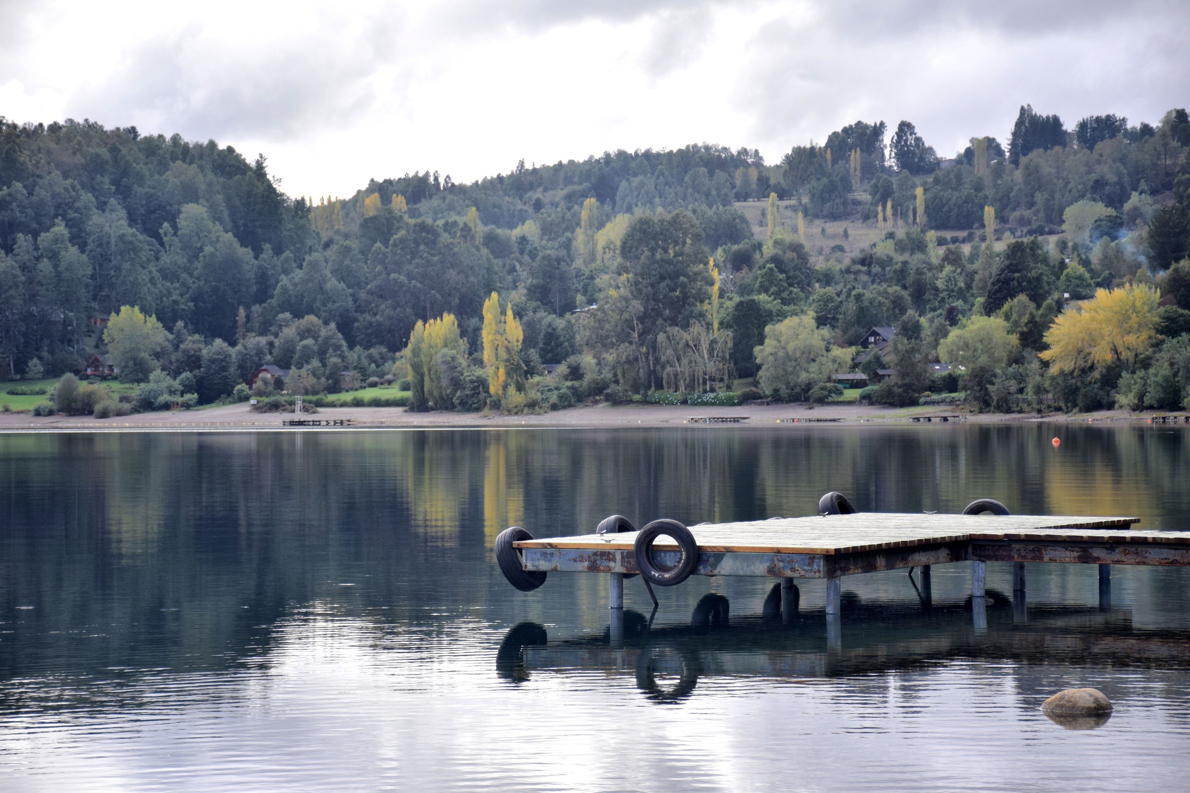 A lake with a wooden dock and tires.