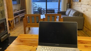 Hyggelig hyttekrog med et træbord, en bærbar computer, en sofa og et fjernsyn.