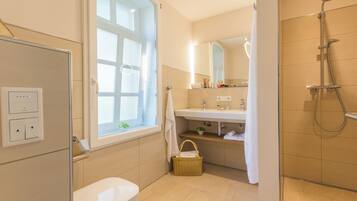 A modern bathroom with a toilet, a shower, a sink, and a window.