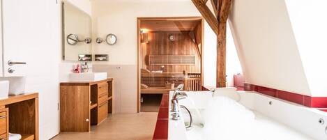 Un baño moderno con tocador de madera, una bañera grande y una zona de sauna.