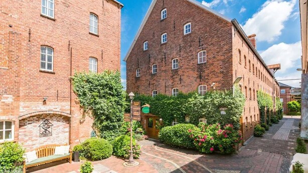 Een binnentuin met bakstenen gebouwen, een bankje en potplanten.