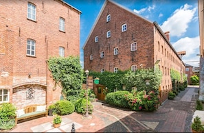 A courtyard with brick buildings, a bench, and potted plants. - Tides Boutique Hotel (Norden)