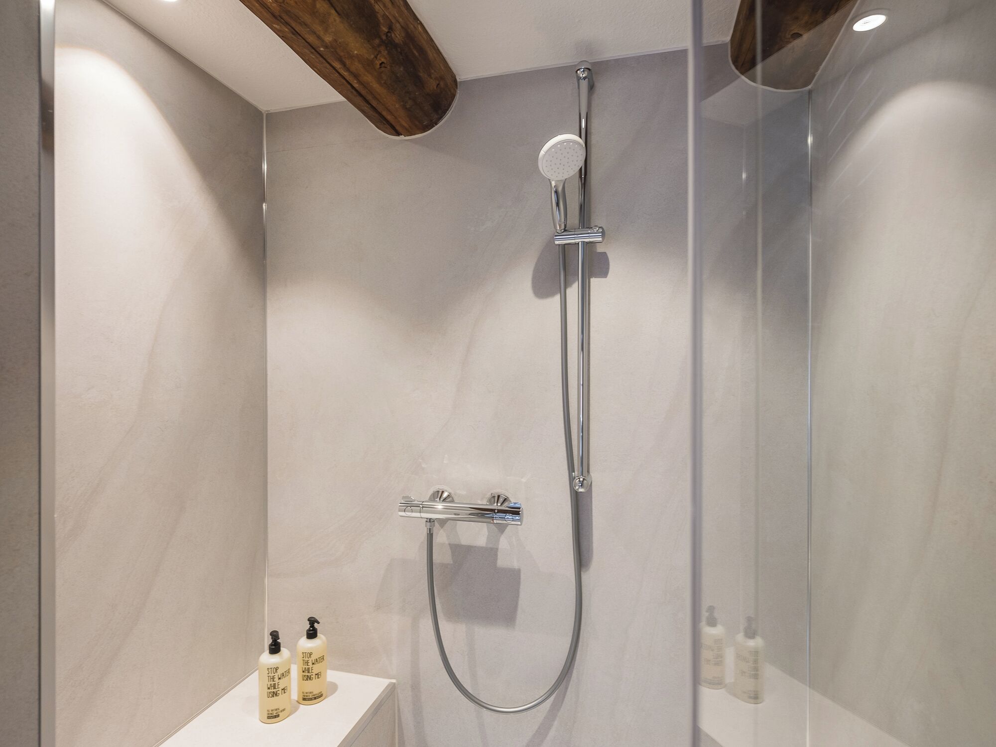 A modern shower with a handheld showerhead and a rain shower attachment.