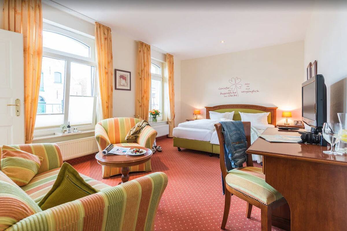 Une chambre d’hôtel comprenant un lit, un canapé, une chaise, un bureau et un téléviseur.