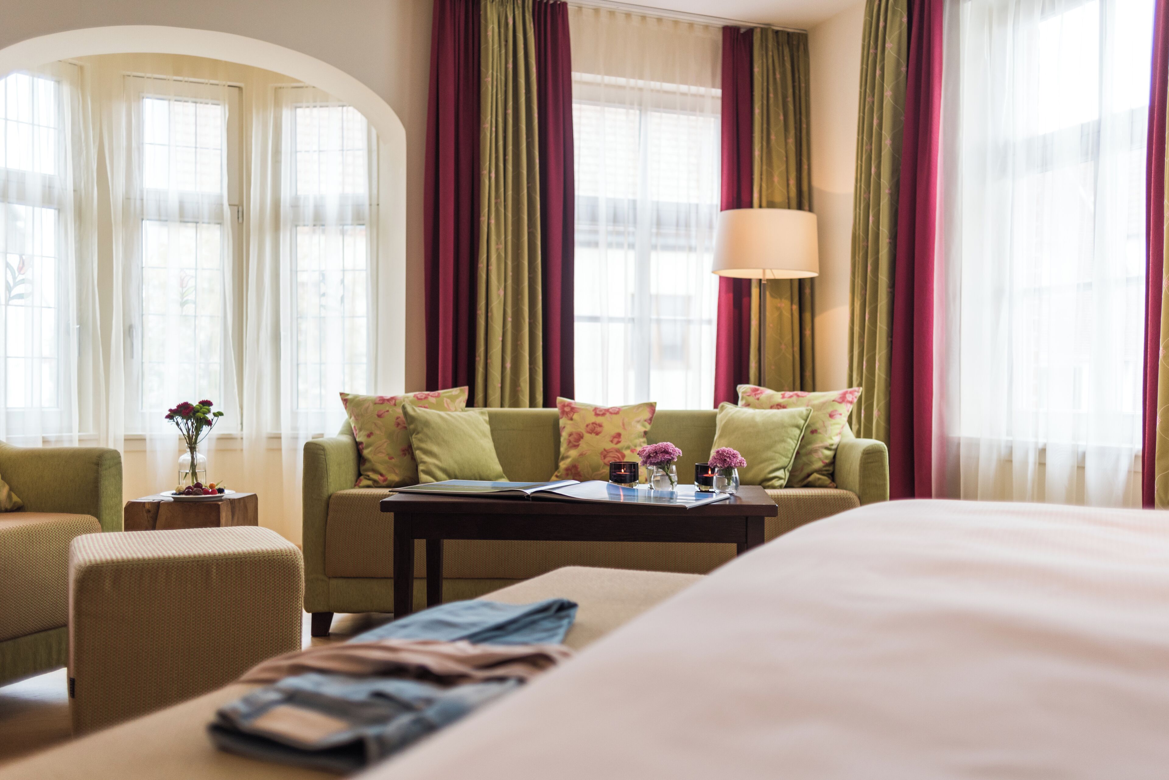 A hotel room with a bed, a sofa, a coffee table, and a window with curtains.