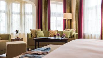 A hotel room with a bed, a sofa, a coffee table, and a window with curtains.