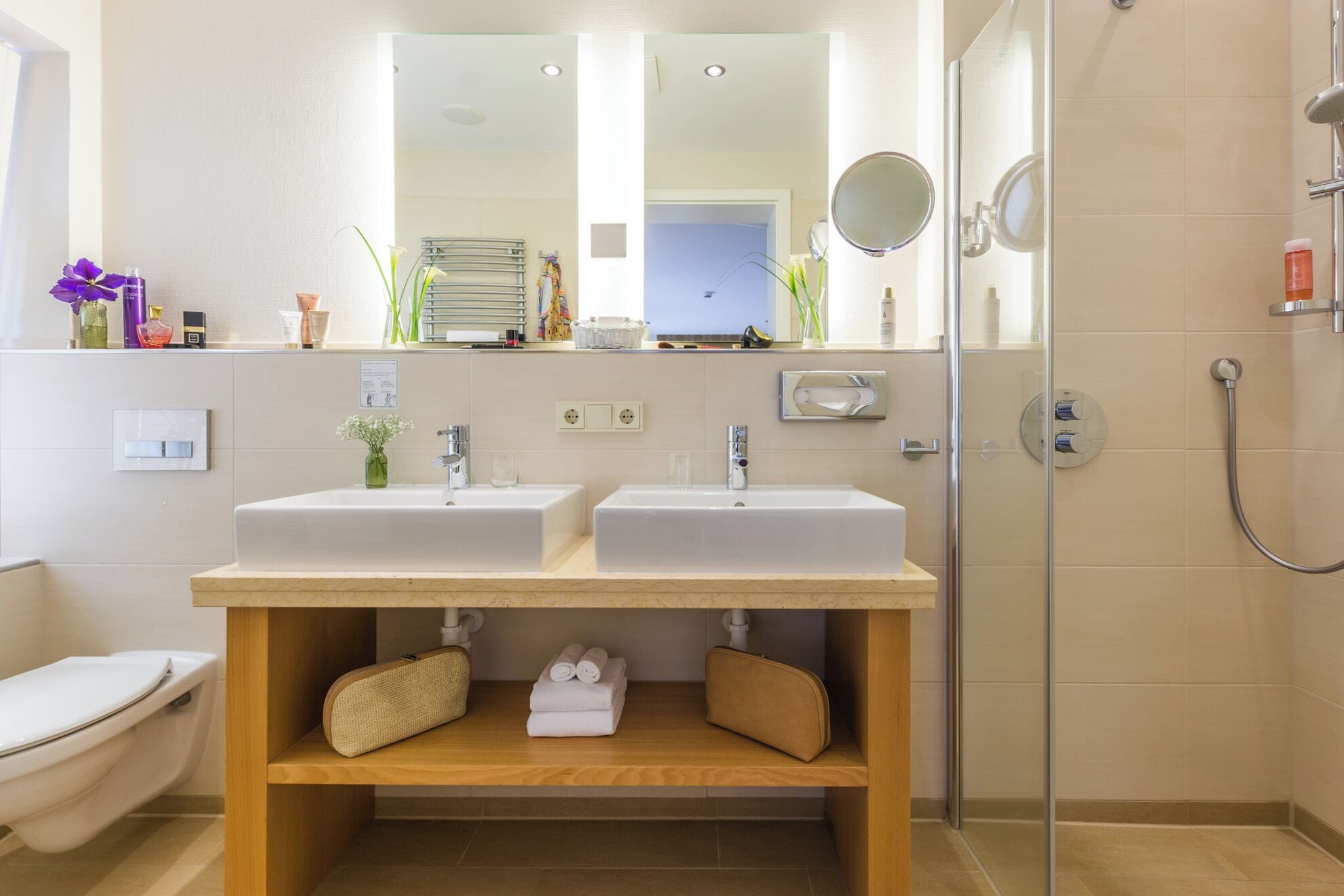 Ein modernes Badezimmer mit zwei Waschbecken, einer Dusche und einem Spiegel.