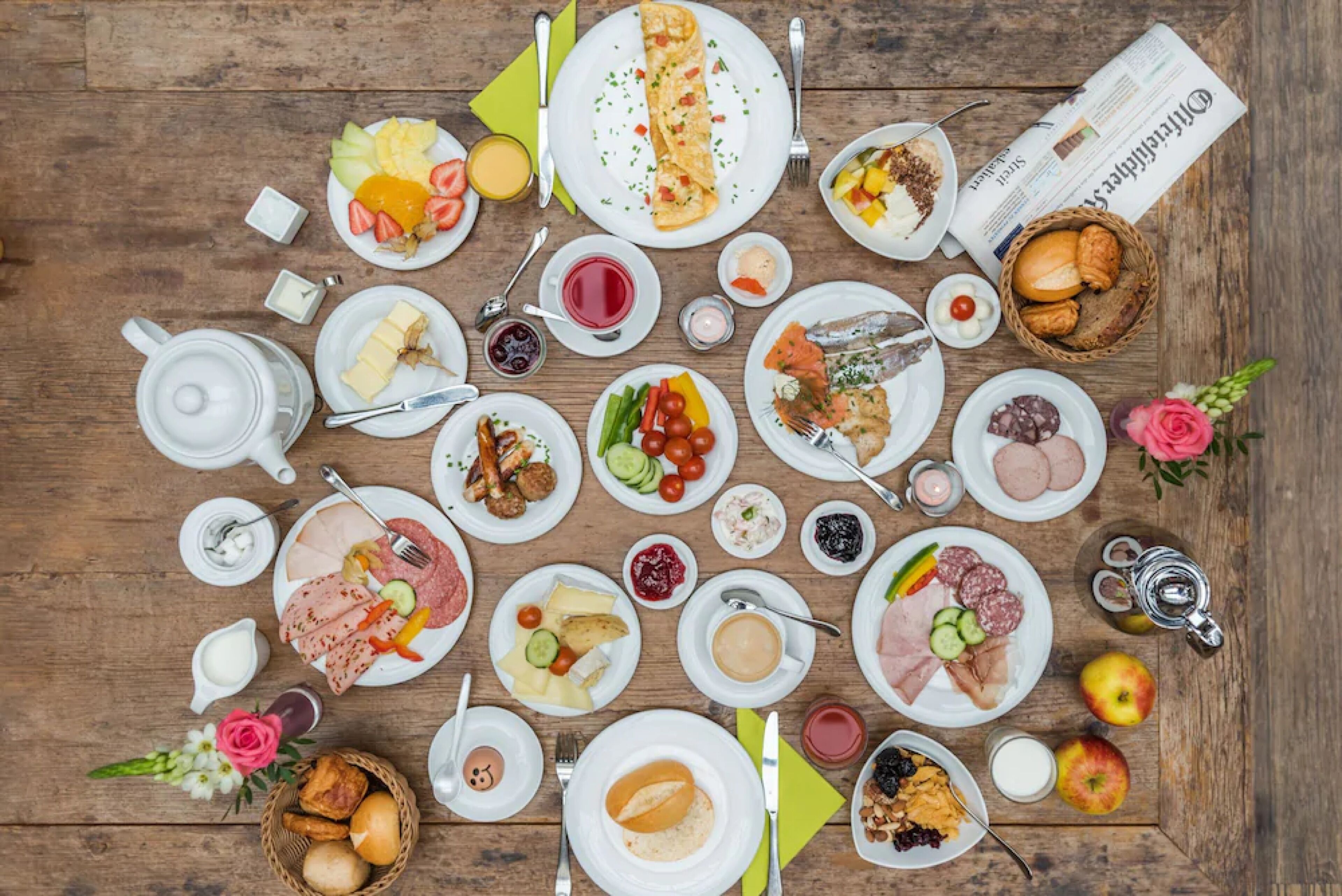 Una mesa con diversos alimentos, como platos de carne, queso y frutas, dispuestos sobre una superficie de madera.