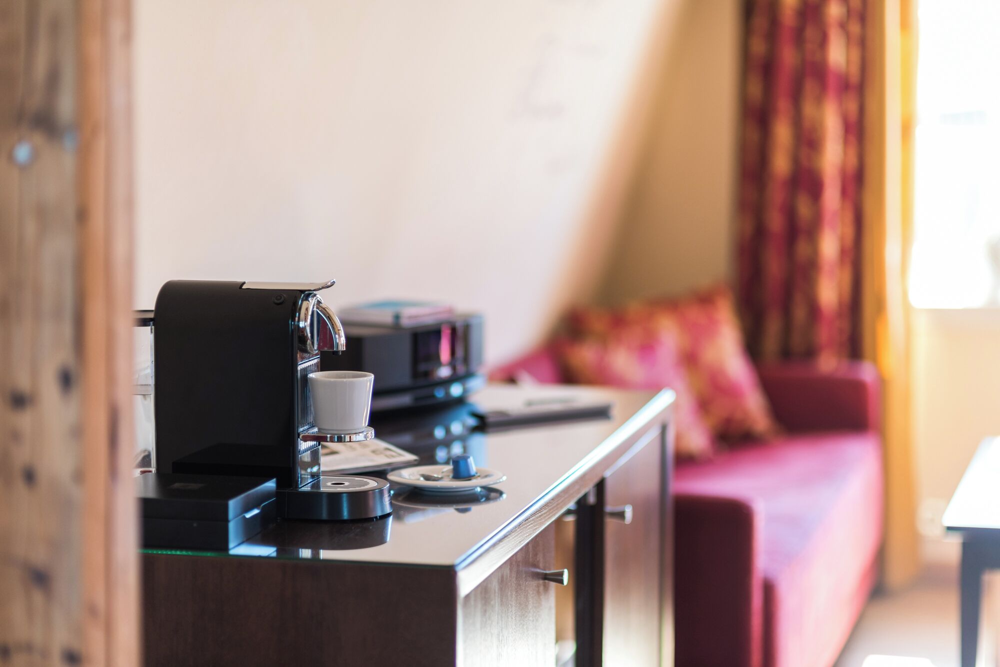 A kitchenette with a coffee machine, a cup, and a small table.