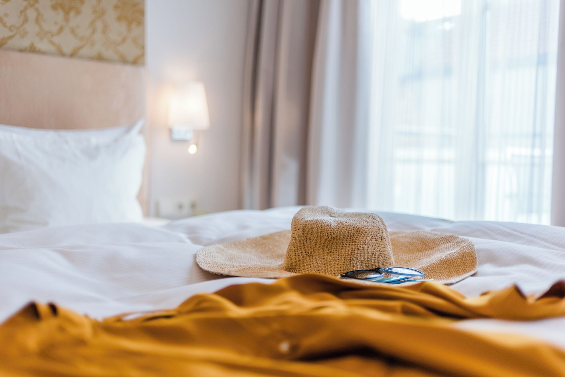 Una cama con un sombrero de paja y un par de gafas.