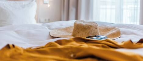 Un lit sur lequel sont posés un chapeau de paille et une paire de lunettes.