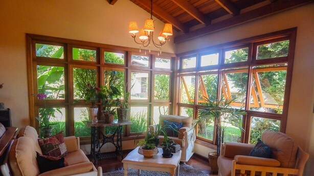 Una sala de estar acogedora con ventanas grandes, techo de madera y una araña.
