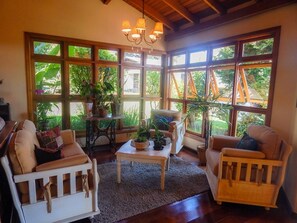Una sala de estar acogedora con ventanas grandes, techo de madera y una araña.