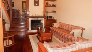 Una sala de estar con chimenea, muebles de madera, un sofá y un perro.