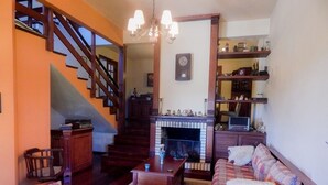 Una sala de estar con chimenea, escalera de madera y un sofá.