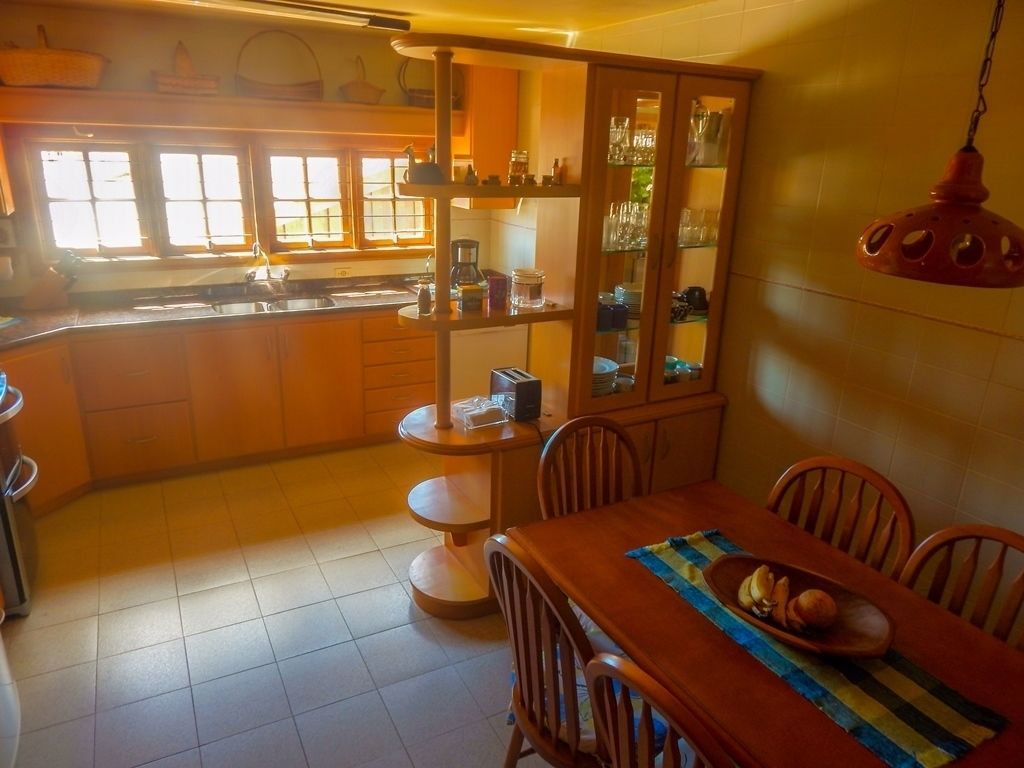 A kitchen with wooden cabinets, a dining table with chairs, and a hanging light fixture.