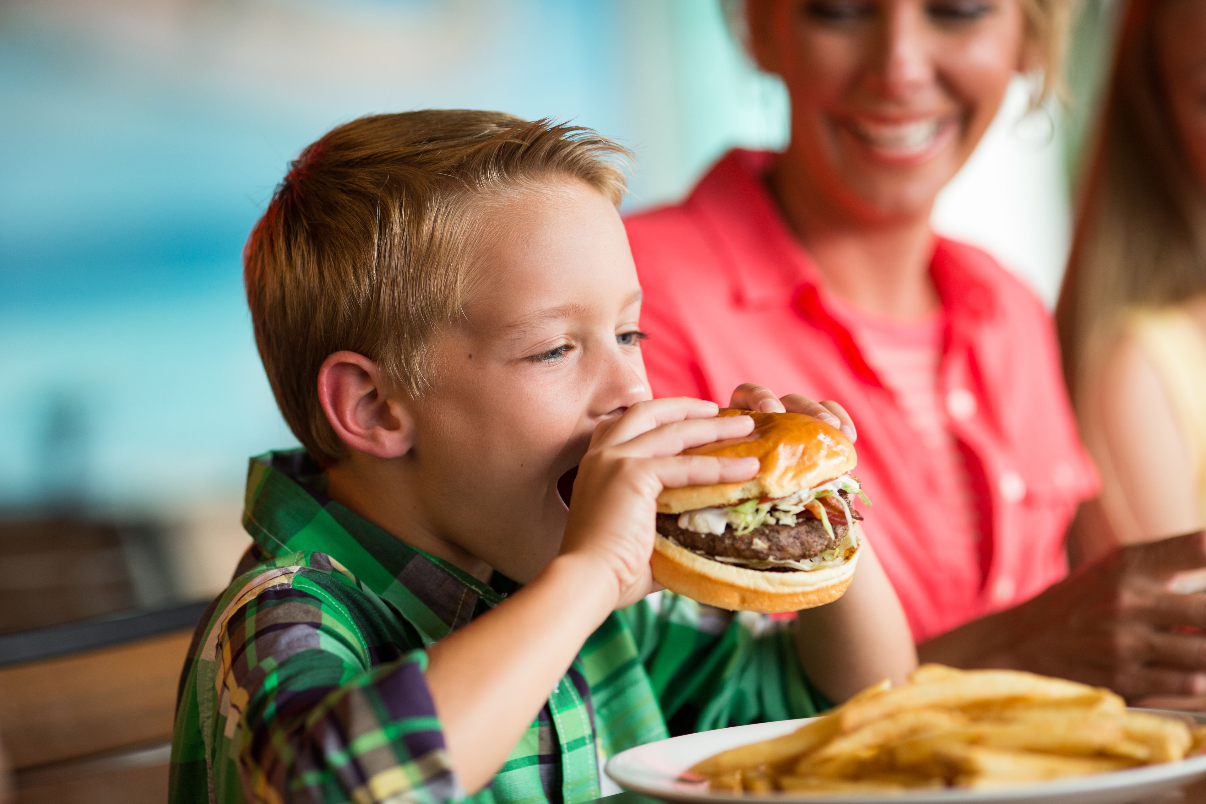 A child eating a burger and fries.