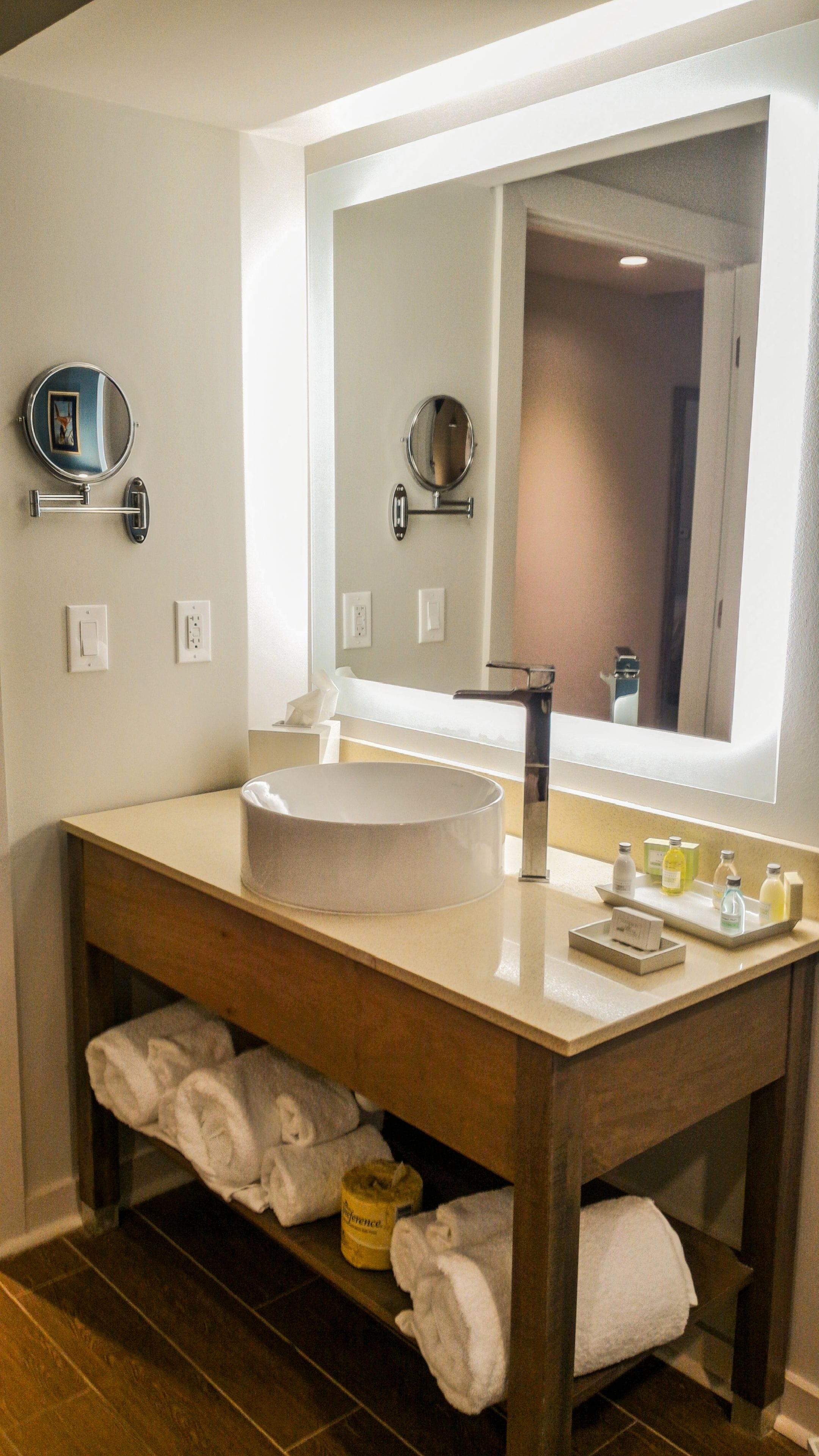 A modern bathroom with a large sink, a mirror, and a towel rack.