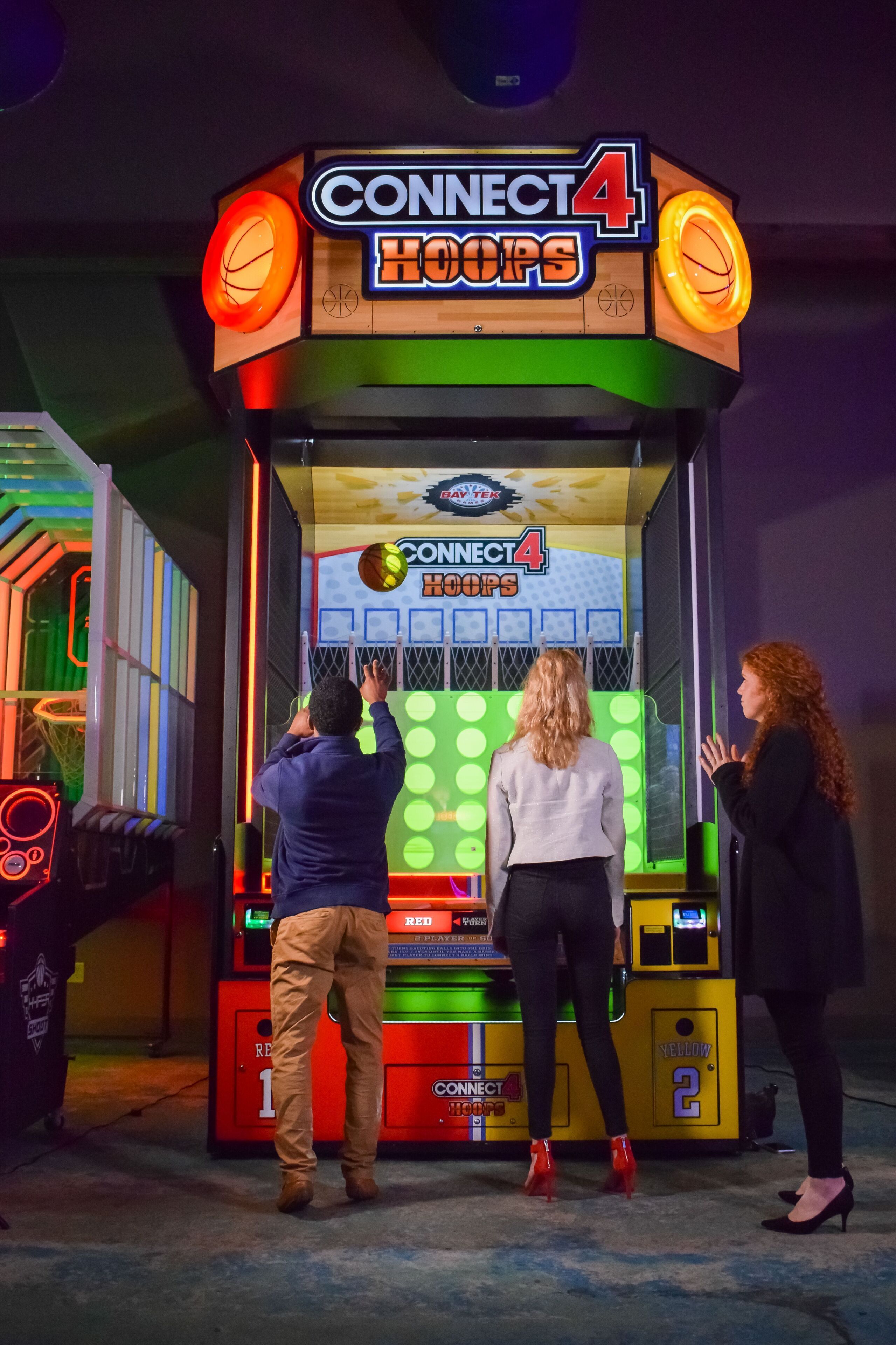Máquina de arcade Connect 4 Hoops con aro de baloncesto, marcador y secciones para los equipos Rojo y Amarillo.