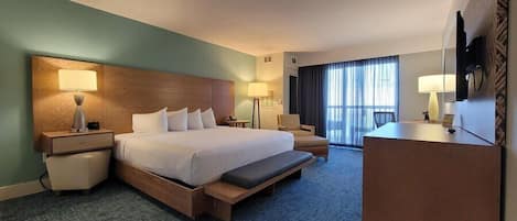 A hotel room with a large bed, bedside tables, a desk, and a chair.