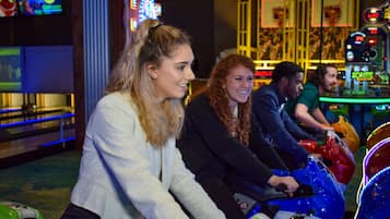 A group of people riding bumper cars in an indoor amusement area.
