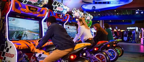 A racing arcade with multiple racing game machines, featuring vibrant neon lights and a futuristic design.