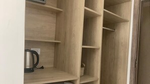 A kitchen with a white refrigerator, a kettle, and a shelf with a basket. - Hotel Altair (San Clemente)