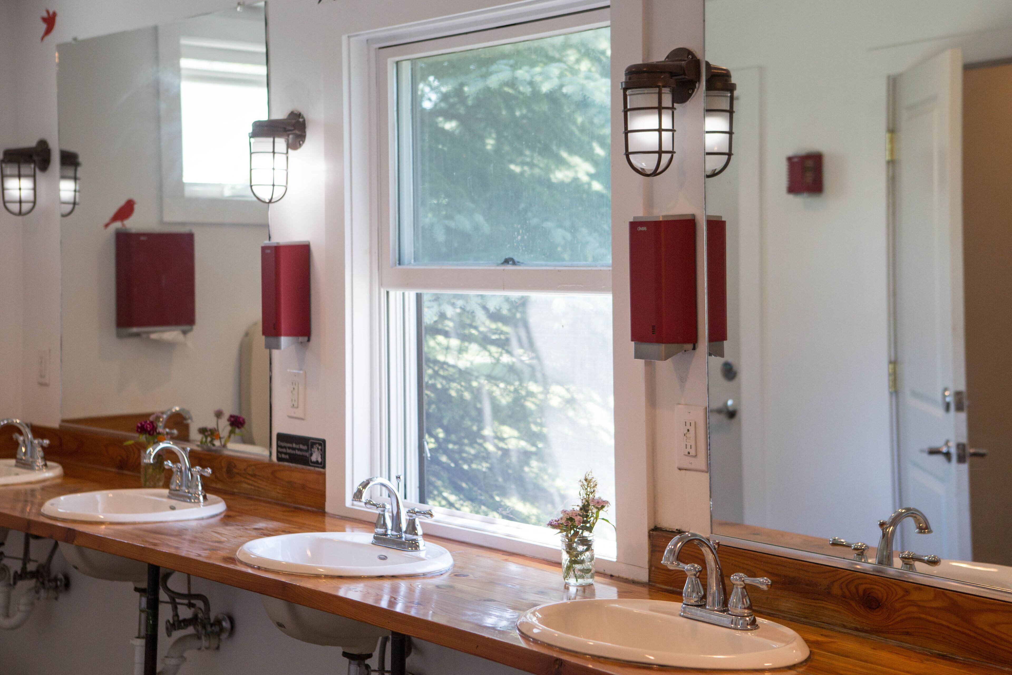 A bathroom with three sinks, wooden countertops, and a large mirror.