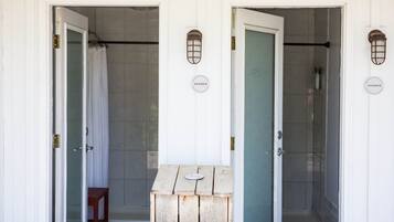 Two shower doors with a wooden bench and a metal lantern between them.