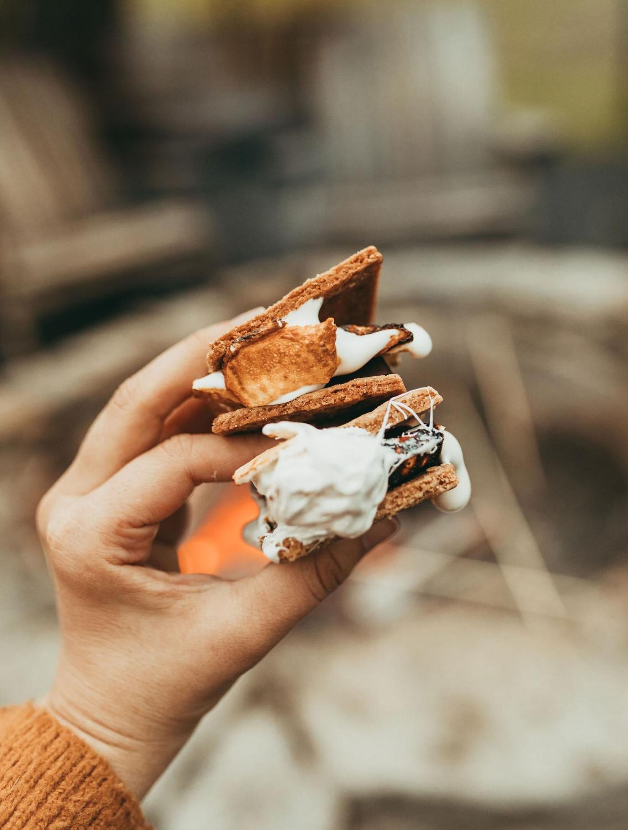 Une main tenant un « s’more », un biscuit graham garni de guimauve et de chocolat.