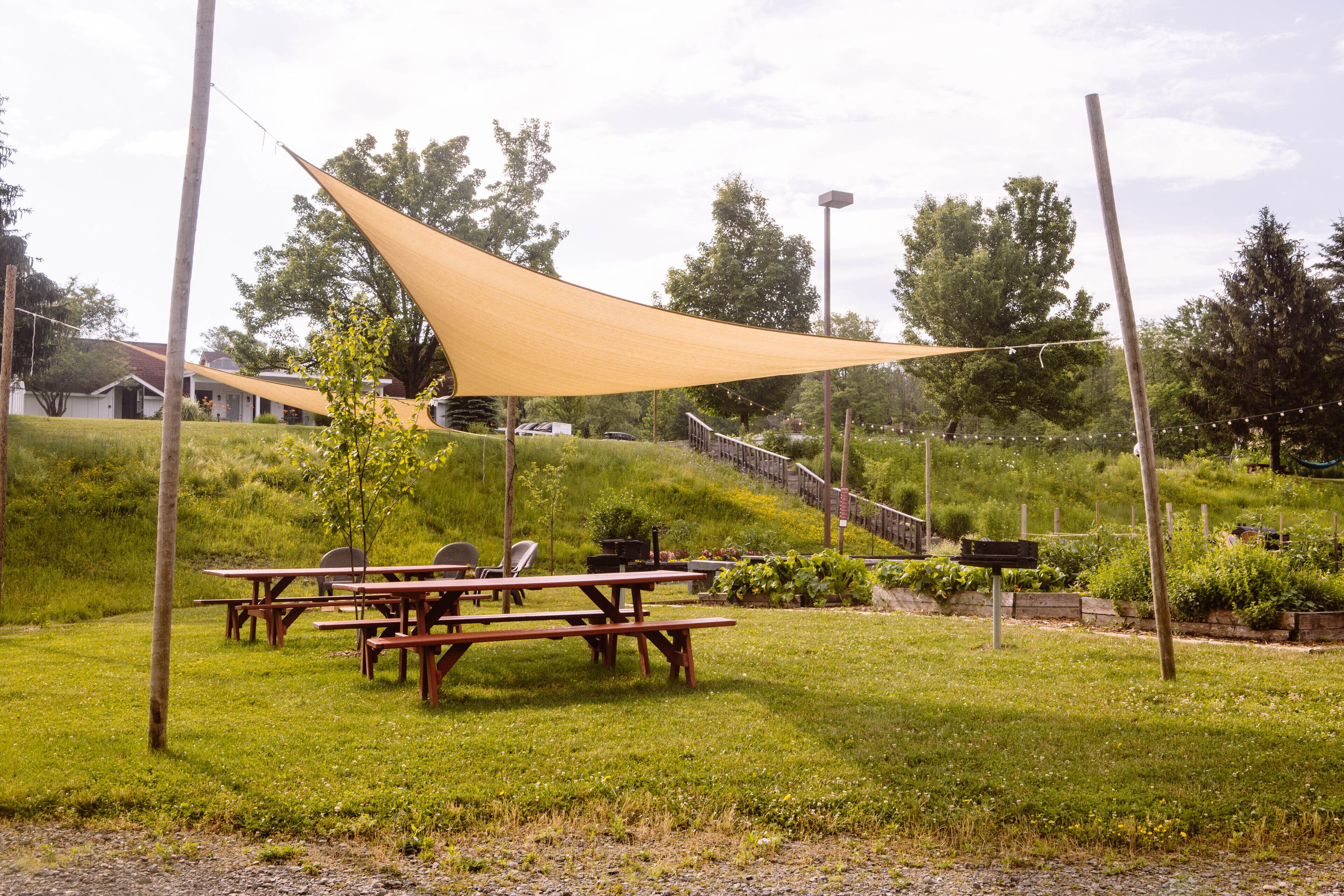 A picnic area with wooden benches and a large shade sail.