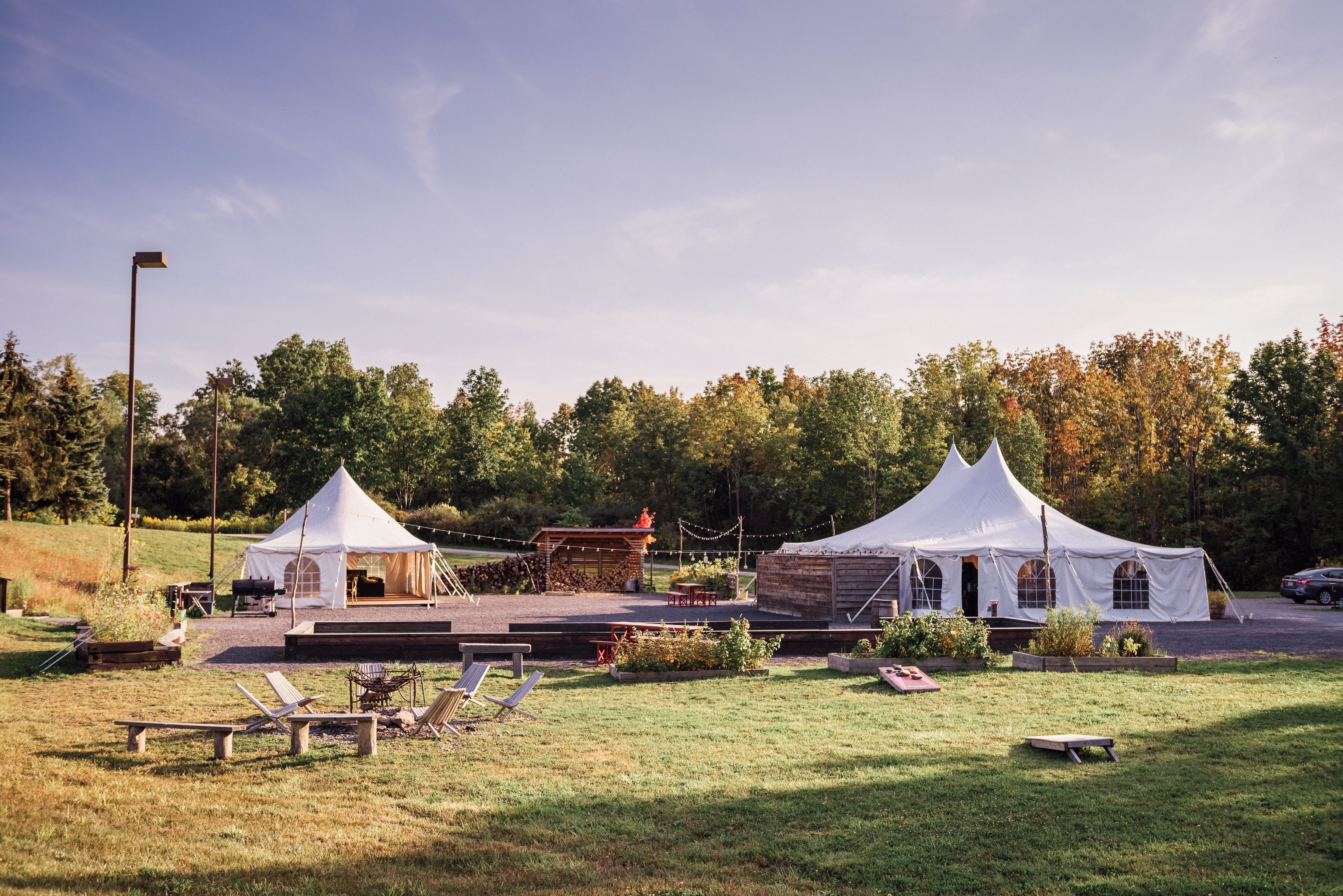 Two white tents with attached structures, a grassy area with lounge chairs, and a paved walkway.