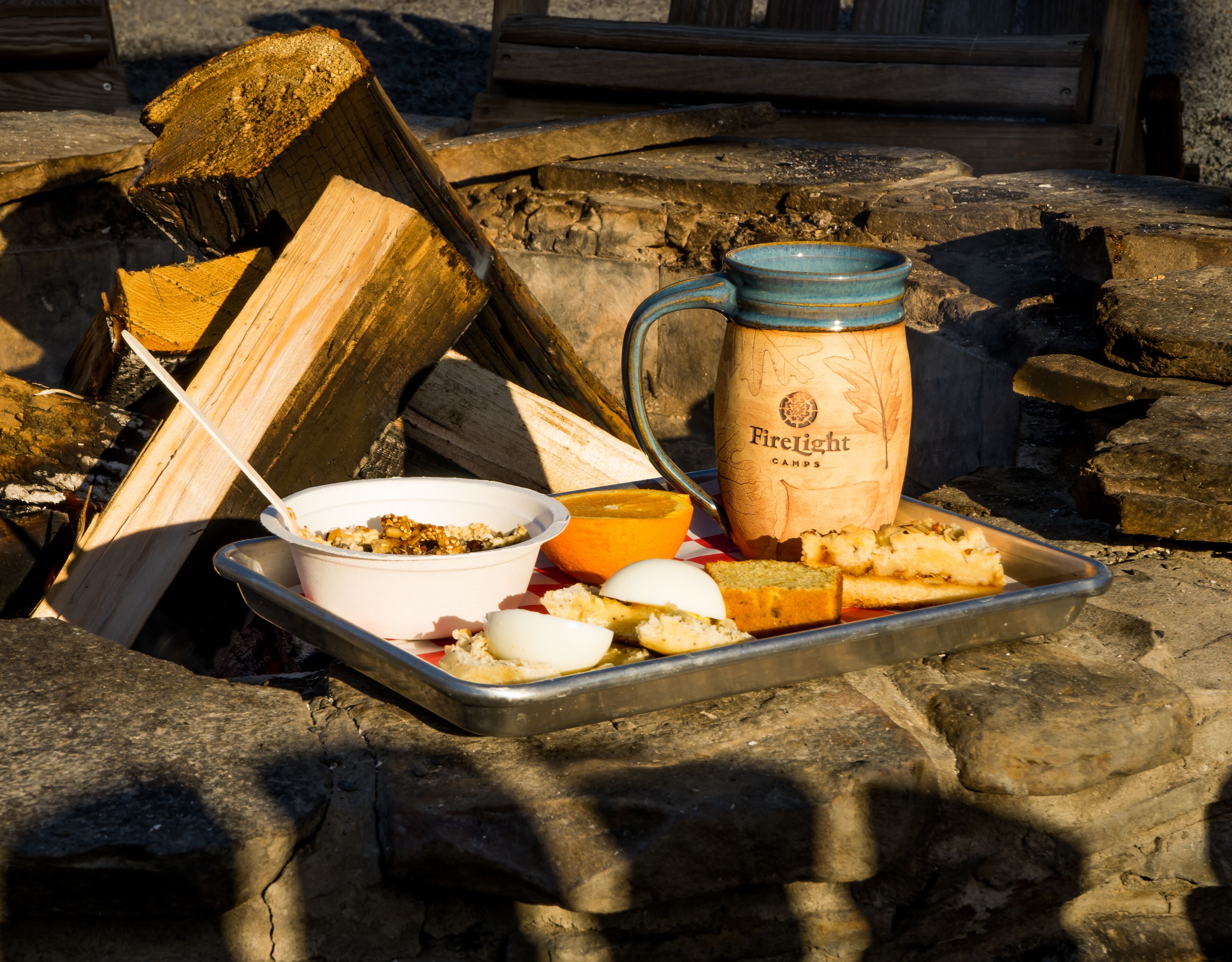Una bandeja con alimentos, una taza con la etiqueta "Firelight Camps" y un tazón de avena.