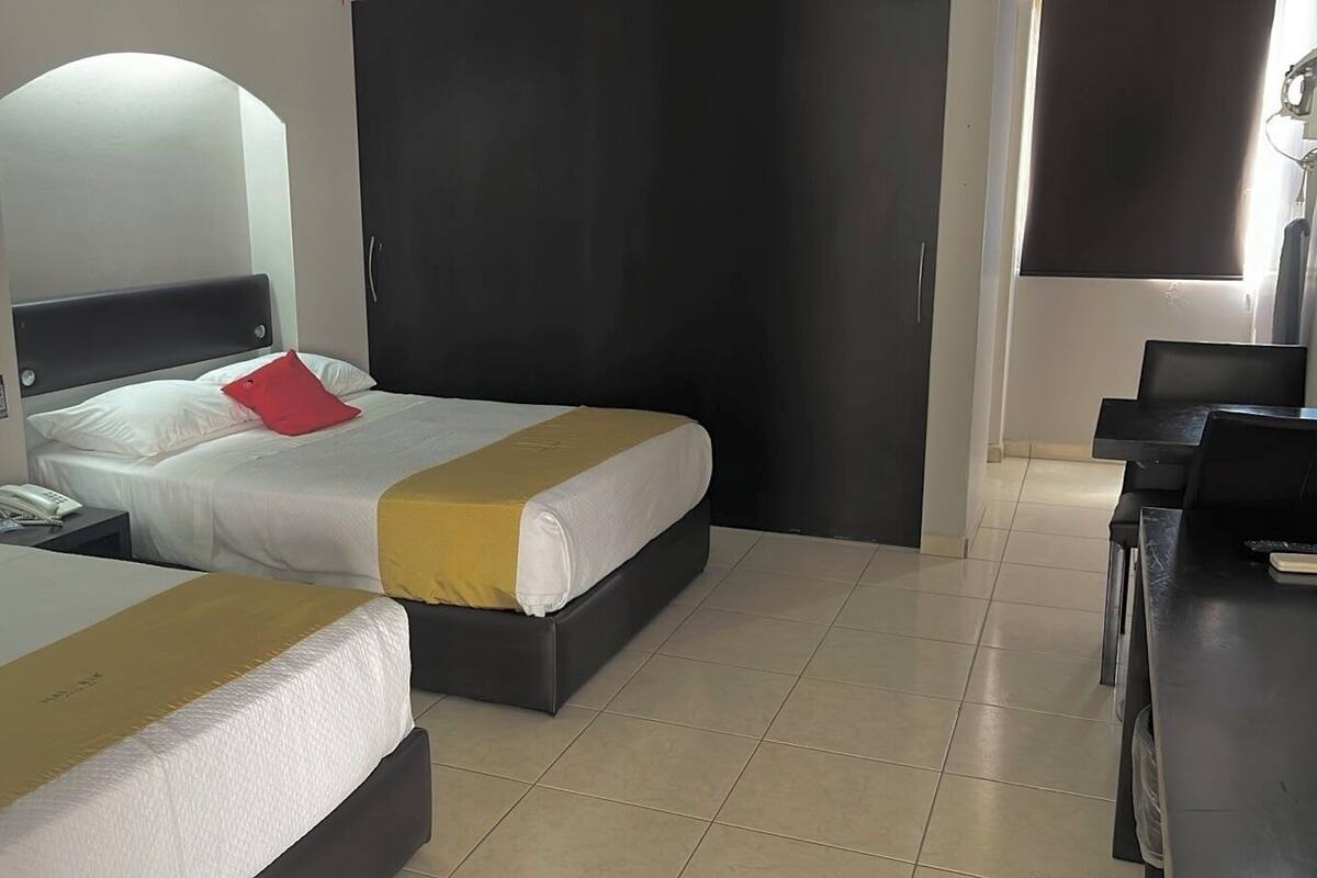 Habitació d'hotel amb dos llits, un escriptori i una cadira.