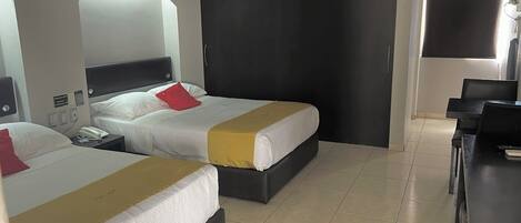 Habitación de hotel con dos camas, un escritorio y una silla.