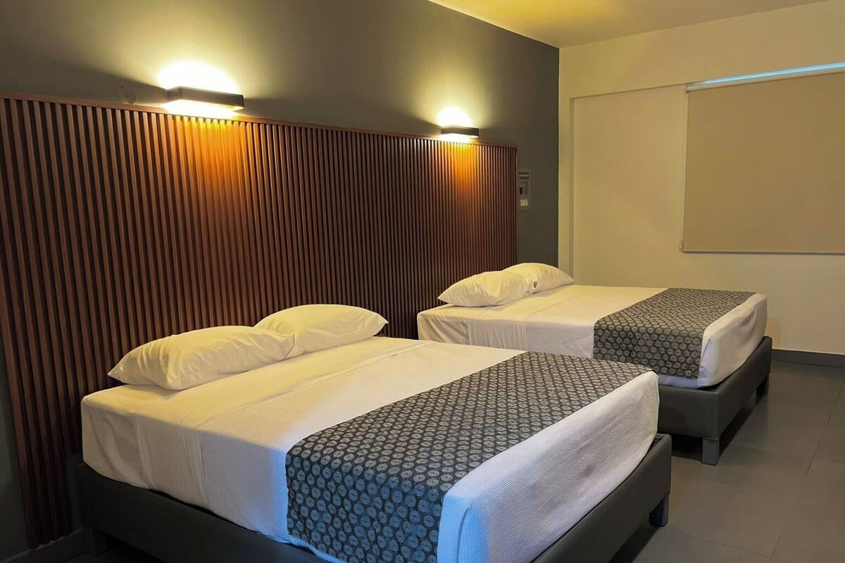Una habitació d'hotel amb dos llits, cadascun amb roba de llit blanca i estores amb dibuixos.