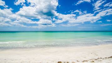 En la playa, playa de arena blanca, camastros y sombrillas